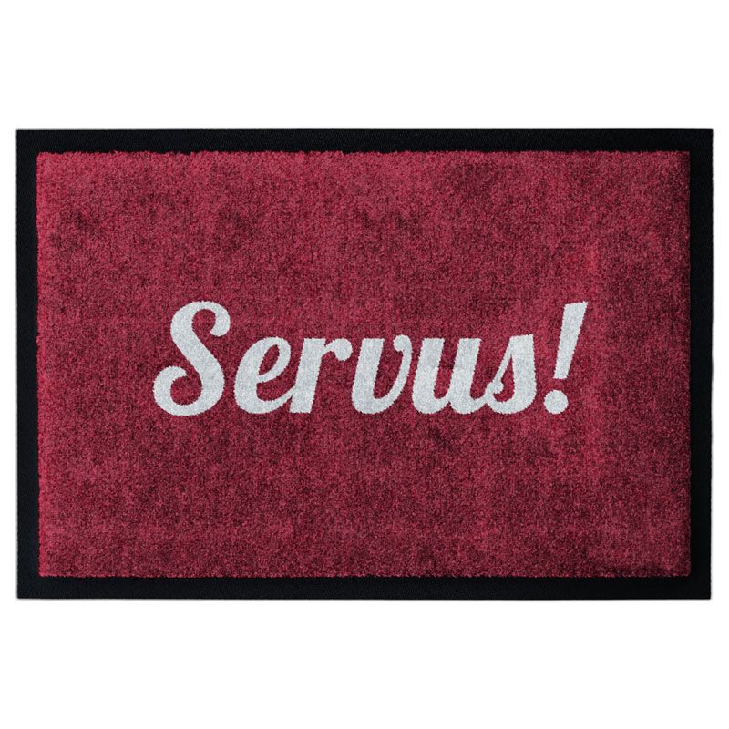 Waschbare Fußmatte von Glücksmatte mit dem Gruß "Servus!" in Hellgrau auf Rot. Mit Rand.