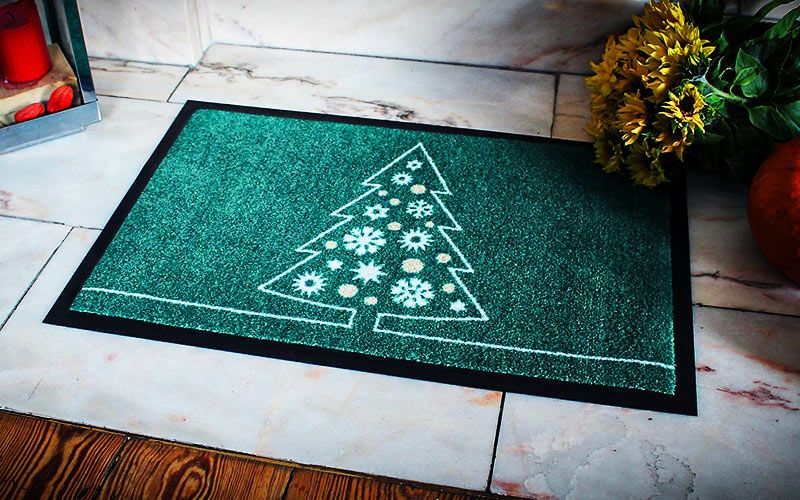 weihnachtliche Fußmatte mit einem Tannenbaum auf grünem Grund