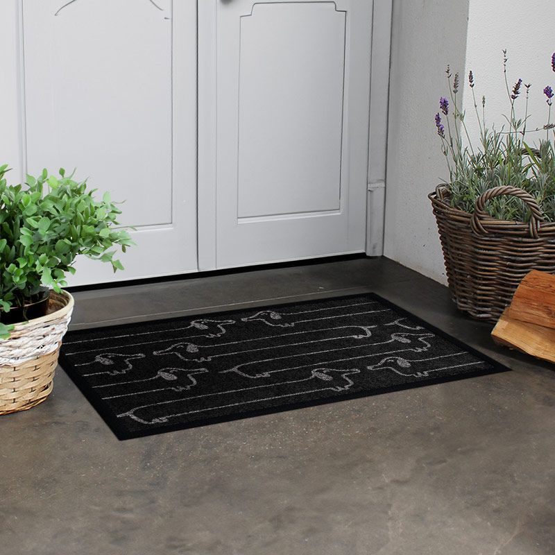 Waschbare Fußmatte von Glücksmatte mit vielen lustigen Dackeln darauf. Schwarz-Weiß. Beispielbild.