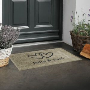 Beispielbild der Fußmatte „Zwei Herzen“ in Beige mit Wunschtext. Waschbar und rutschfest. Ohne Gummirand.